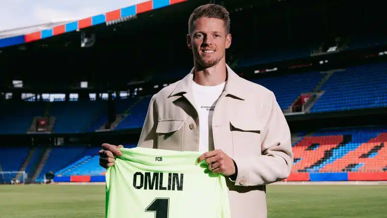 omlin bâle | AllezPaillade.com Football player on a stadium field holding a neon green jersey that reads 'OMLIN' and number 1, smiling at camera.