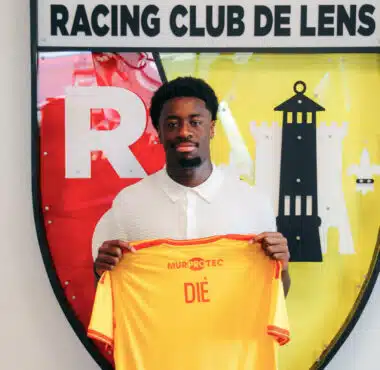 Young man in a white polo holds up a bright yellow jersey in front of the Racing Club de Lens crest.