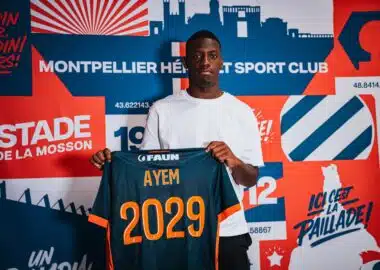 Grégory Ayem signature | AllezPaillade.com Young man wearing a white shirt holds up a dark blue sports jersey with orange '2029' and the name AYEM.