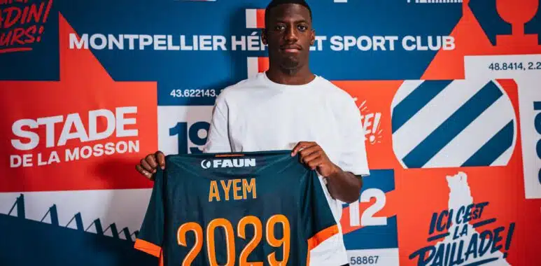 Grégory Ayem signature | AllezPaillade.com Young man wearing a white shirt holds up a dark blue sports jersey with orange '2029' and the name AYEM.