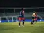 Soccer player wearing blue jersey number 5 stands on a green field during a night match, near teammates and a goalie in the background.