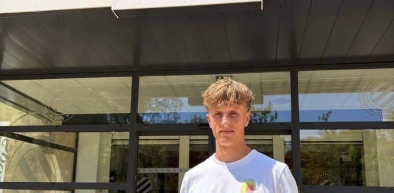 Young man stands outside Montpellier H&eacute;rault Sport Club, holding a red-and-navy team jersey in front of the storefront sign.