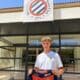 Young man stands outside Montpellier H&eacute;rault Sport Club, holding a red-and-navy team jersey in front of the storefront sign.