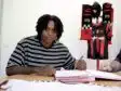 Screenshot | AllezPaillade.com Person signing documents at a table with a Flamengo jersey and scarves displayed in the background, suggesting a contract signing.
