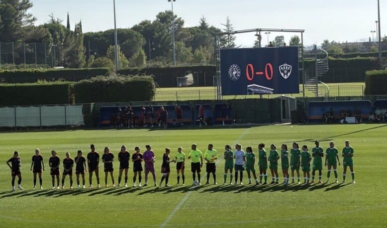 Screenshot | AllezPaillade.com Lineups of two soccer teams shaking hands before a match on a sunny field, scoreboard showing 0-0 in the background