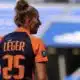 Soccer player seen from behind wearing an orange and navy jersey with the name L&Eacute;GER and number 25 on the back, in a stadium.