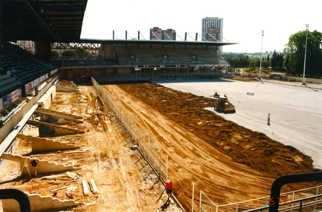 MOSSON_03 | AllezPaillade.com Stadium under renovation with a long dirt trench along the field and heavy construction equipment visible on the dirt surface.