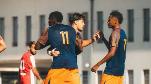 Two soccer players celebrate together on the field, wearing blue jerseys and orange shorts, with the number 11 on one player's back.