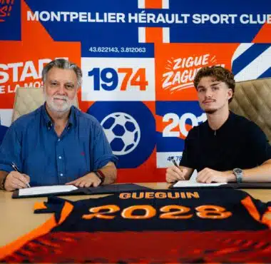 Two men sit at a table, signing documents, with a bright blue and orange sports club backdrop behind them.