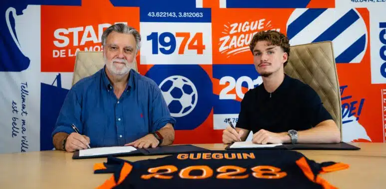 dsc00093-scaled | AllezPaillade.com Two men sit at a table, signing documents, with a bright blue and orange sports club backdrop behind them.