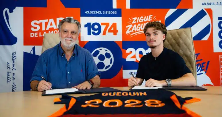 dsc00093-scaled | AllezPaillade.com Two men sit at a table, signing documents, with a bright blue and orange sports club backdrop behind them.