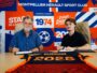 Two men sit at a table, signing documents, with a bright blue and orange sports club backdrop behind them.