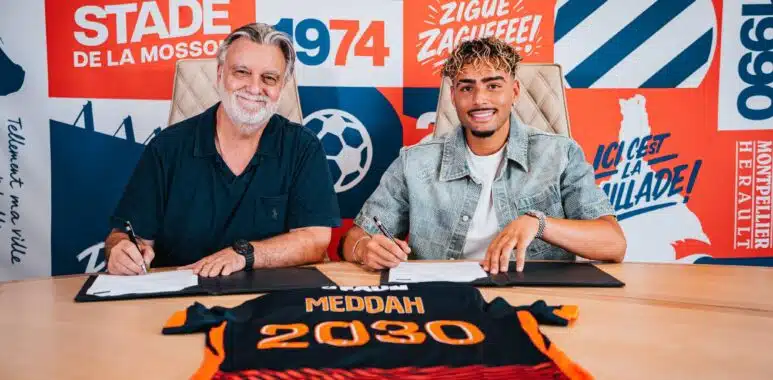 dsc00175-2048x1365 | AllezPaillade.com Two men sit at a table signing documents, with a bright graphic wall behind them.",