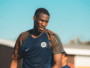 Male soccer player in a dark blue training jersey on a sunny day, focused during practice.