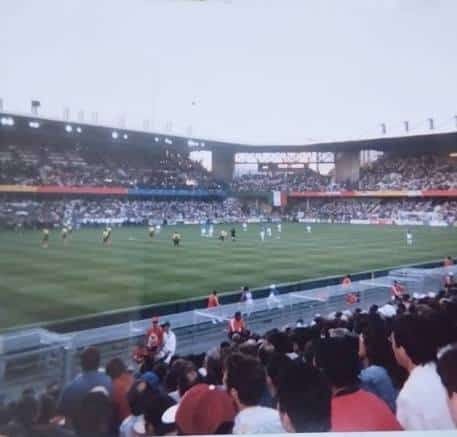 images 19 | AllezPaillade.com Soccer match in a large stadium with spectators in the stands and players on a green field at center.