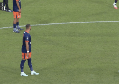 Soccer players in blue and orange uniforms stand near the center line; ball sits on the field as a 0-0 scoreboard and timer appear on screen (00:22) with a beIN SPORTS logo.