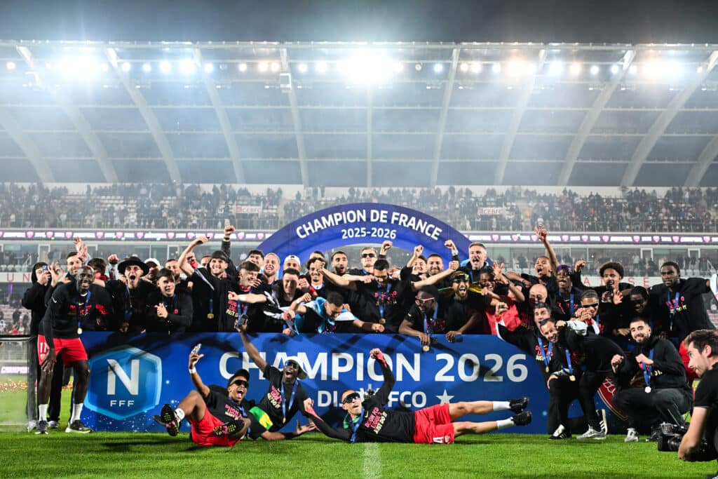 Dijon FCO v Orleans US 45 - National 1 20252026 | AllezPaillade.com Soccer team celebrating a championship on the field under bright stadium lights, with a blue banner reading Champion 2025-2026 in front of cheering stands.