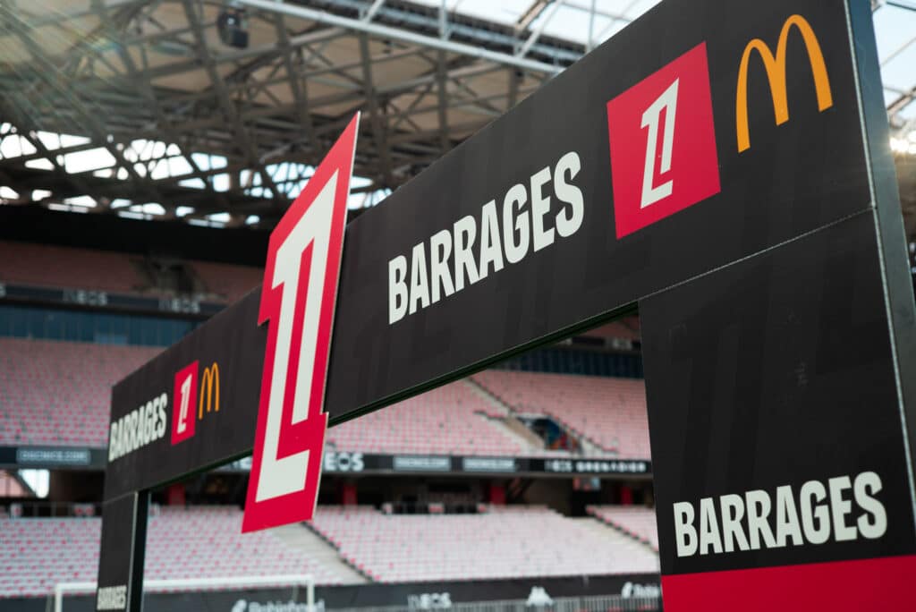 OGC Nice v AS Saint-Etienne - Ligue 1 McDonalds 20252026 - RelegationPromotion Playoffs | AllezPaillade.com Large black event banner with the word BARRAGES and a red '1' marker, golden arches logo visible at top right, stadium seating in the background.