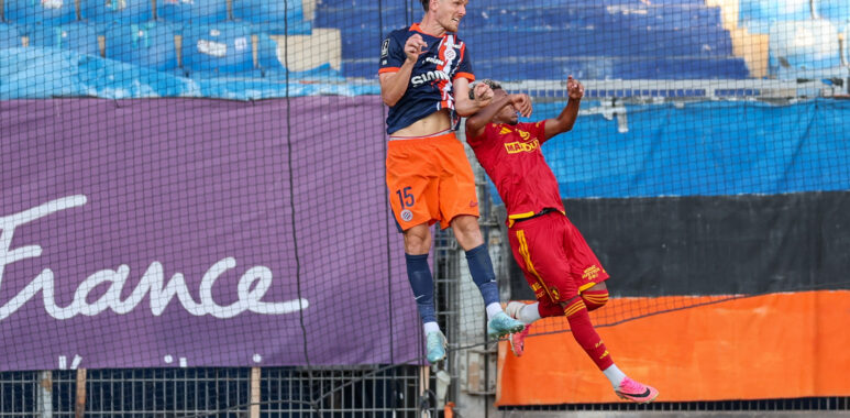 Julien Laporte Montpellier Herault SC v Rodez Aveyron Football - Friendly Match 01082026 | AllezPaillade.com Two soccer players jump for a header near the goal, one in navy/orange and the other in red, with a net and blue seats behind them.