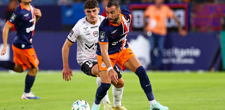 Soccer players in blue-orange and white chase the ball during a match on a sunny field.