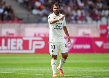 Soccer player in a white kit with number 10, pointing during a match on a green field.