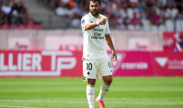 Soccer player in a white kit with number 10, pointing during a match on a green field.