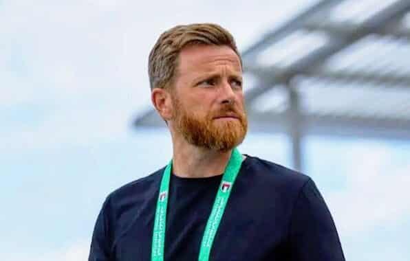 IMG_5474 | AllezPaillade.com Man with a reddish beard wearing a black shirt and a green lanyard, standing outdoors and looking to the right.