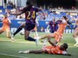 Soccer match scene: a player in a maroon-and-blue jersey (#24) leaps to kick the ball while players in orange defend nearby on a green field.
