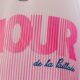 Close-up of a pink striped logo with large bold letters on white fabric; blue cursive text reads 'de la Paillade'.
