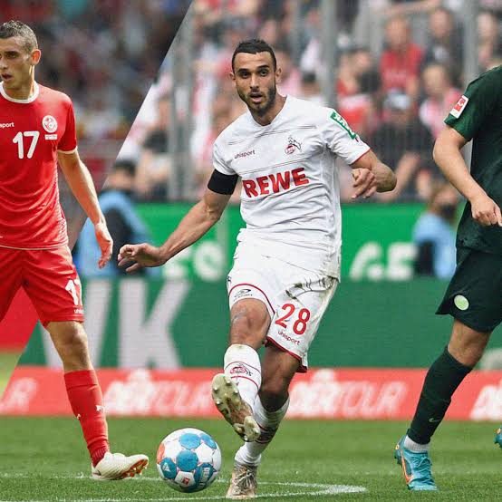 skhiri cologne | AllezPaillade.com Soccer player in a white jersey number 28 dribbles the ball during a match, with red- and dark-clad opponents nearby.