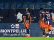 Three soccer players in blue and orange kits walk along the sideline, backs to the camera; jersey numbers 17 and 23 visible, with advertising boards in the background reading Montpellier M&eacute;tropole et Ville.