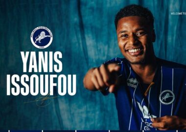Promotional banner: smiling player in blue pinstripe jersey pointing at the camera with Millwall crest and the text 'YANIS ISSOUFOU' on a teal backdrop; 'WELCOME TO MILLWALL' unreadable at top-right.