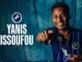 Promotional banner: smiling player in blue pinstripe jersey pointing at the camera with Millwall crest and the text 'YANIS ISSOUFOU' on a teal backdrop; 'WELCOME TO MILLWALL' unreadable at top-right.