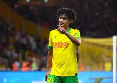 Soccer player in yellow and green kit on the field, pointing with his right hand during a match.